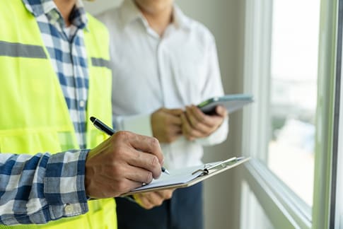 a contractor writing on a paper and man standing besides him